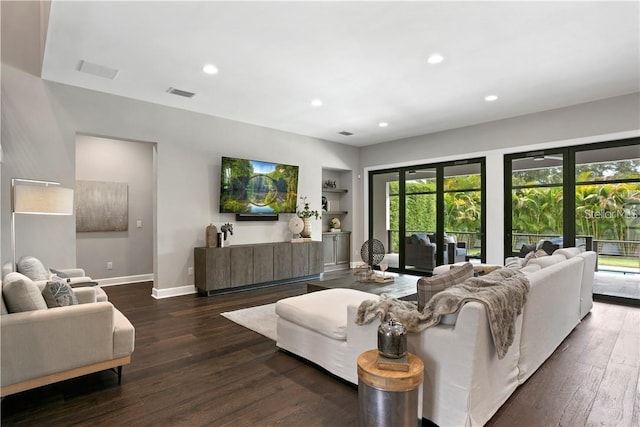 living room with built in shelves and dark hardwood / wood-style floors