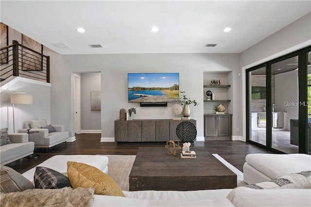 living room with built in shelves and dark hardwood / wood-style flooring