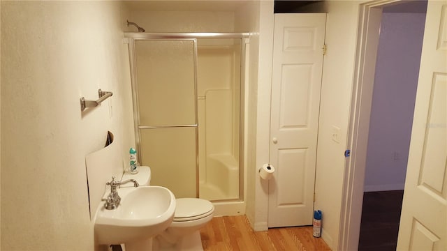 bathroom with toilet, hardwood / wood-style floors, a shower with shower door, and sink