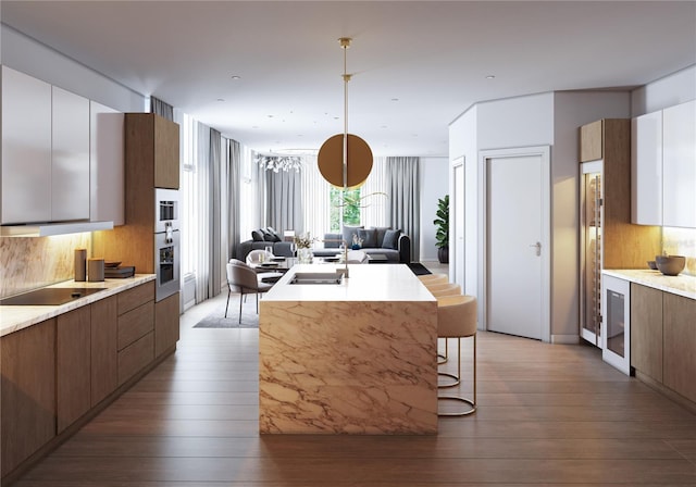 kitchen with a center island with sink, backsplash, white cabinets, and hardwood / wood-style floors