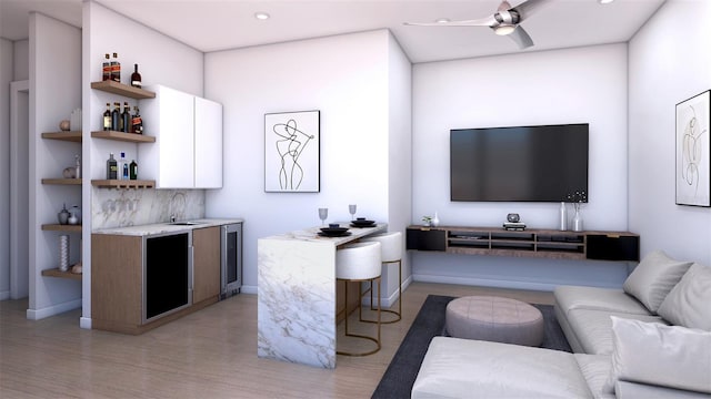 living room featuring sink, light hardwood / wood-style flooring, ceiling fan, and beverage cooler