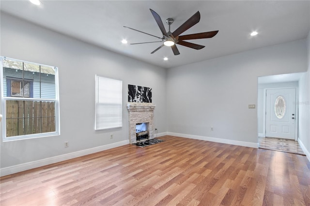 unfurnished living room featuring a fireplace, ceiling fan, and light wood-type flooring