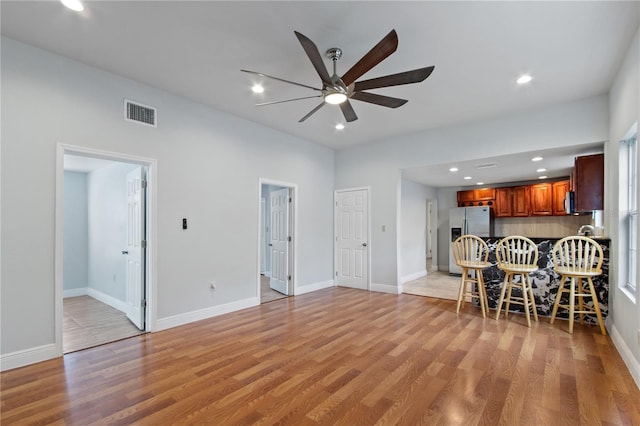 unfurnished living room featuring ceiling fan and light wood-type flooring