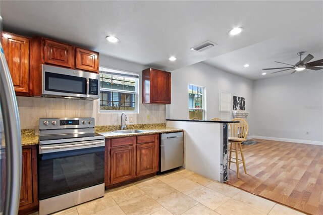 kitchen with appliances with stainless steel finishes, sink, a breakfast bar area, backsplash, and kitchen peninsula