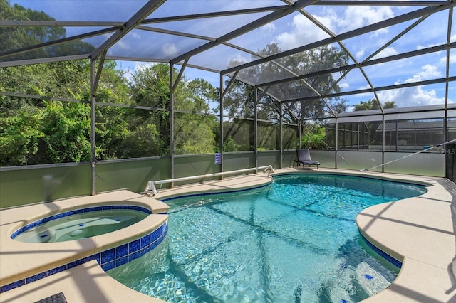 view of pool with a patio, glass enclosure, and an in ground hot tub