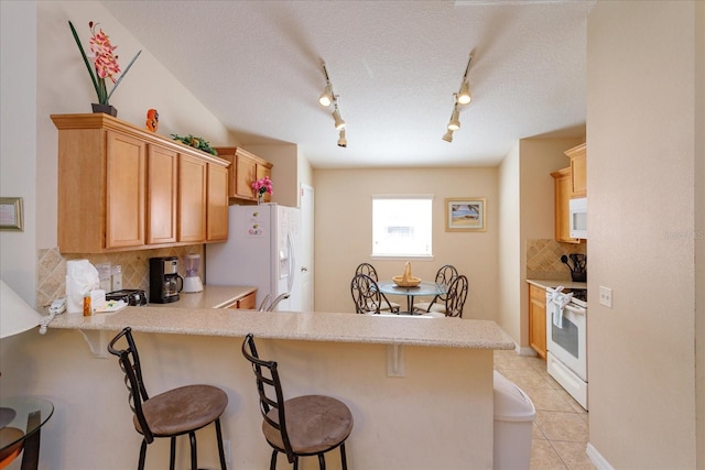 kitchen featuring white appliances, kitchen peninsula, a breakfast bar area, and light tile patterned floors