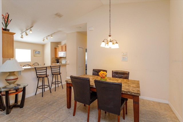 tiled dining area with vaulted ceiling and an inviting chandelier