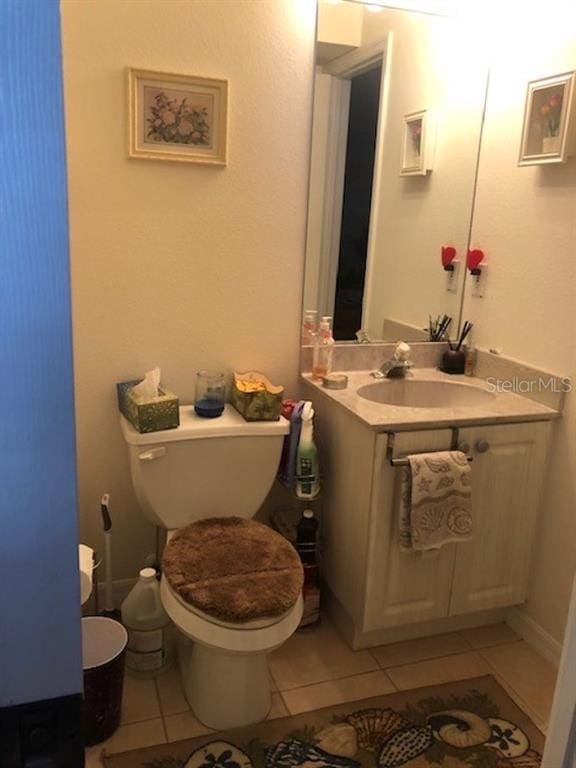 bathroom with toilet, tile floors, and vanity