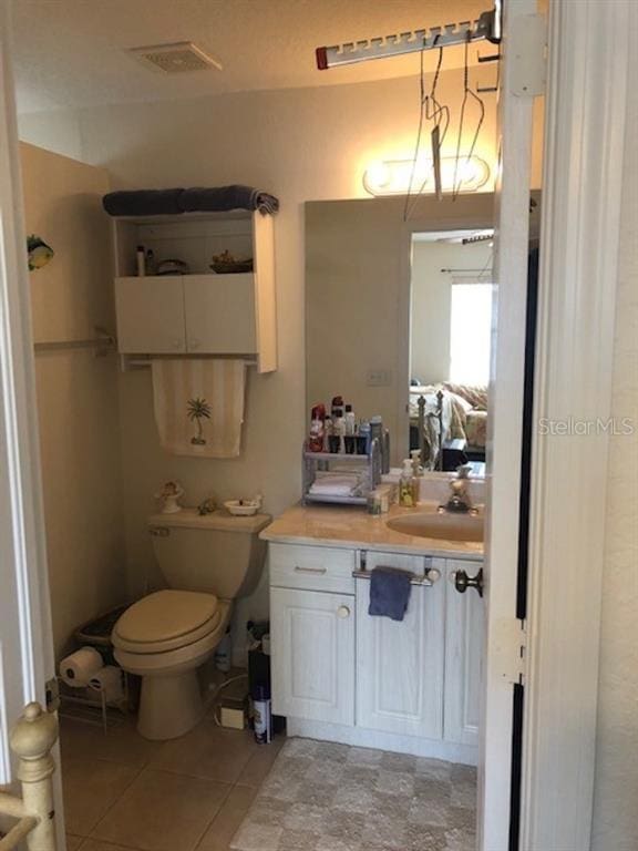 bathroom featuring toilet, tile floors, and vanity