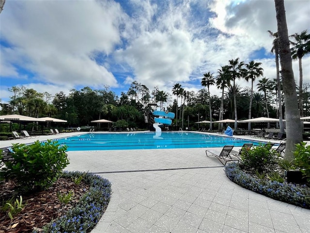 view of pool with a water slide and a patio