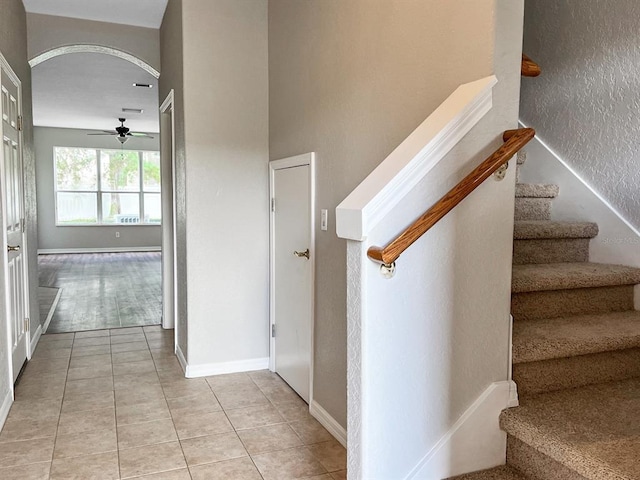 stairway featuring ceiling fan and light tile floors