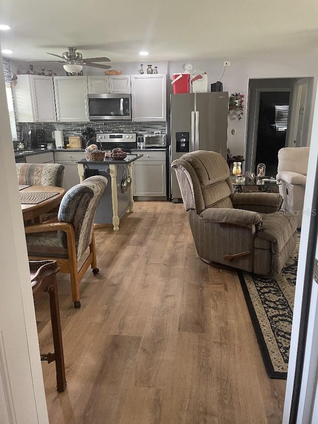 living room featuring ceiling fan and light hardwood / wood-style floors