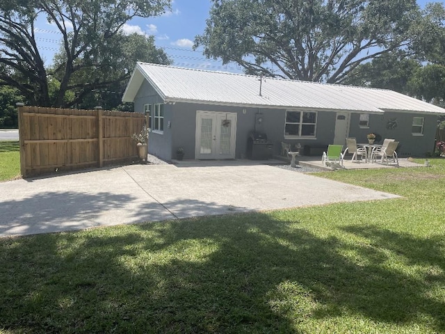 rear view of property featuring a yard, a patio area, and french doors