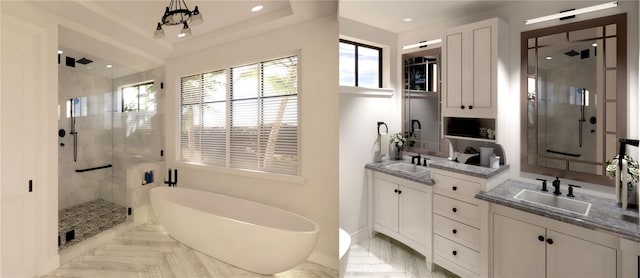 bathroom with a chandelier, shower with separate bathtub, double vanity, and a tray ceiling