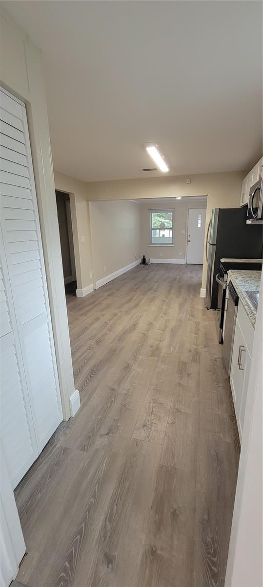 interior space with white cabinets, light wood-type flooring, and appliances with stainless steel finishes