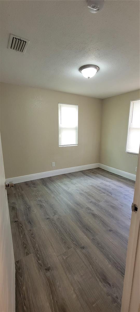 unfurnished room featuring a textured ceiling and dark wood-type flooring