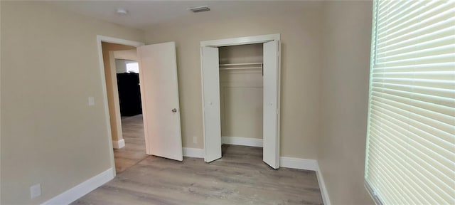 unfurnished bedroom featuring a closet, fridge, and light wood-type flooring