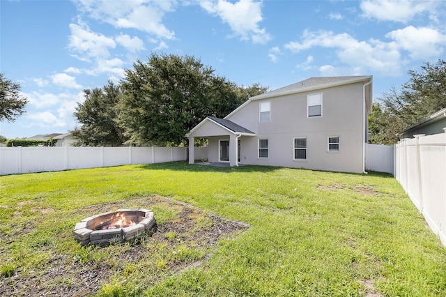 back of property with a yard and an outdoor fire pit