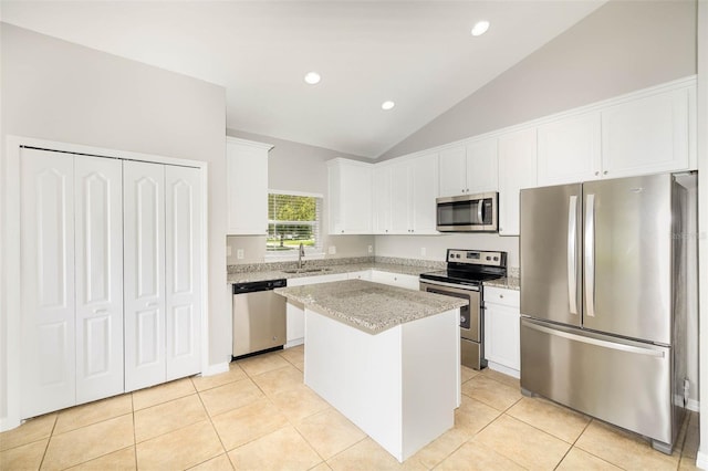 kitchen with light tile patterned flooring, a sink, stainless steel appliances, white cabinetry, and a center island