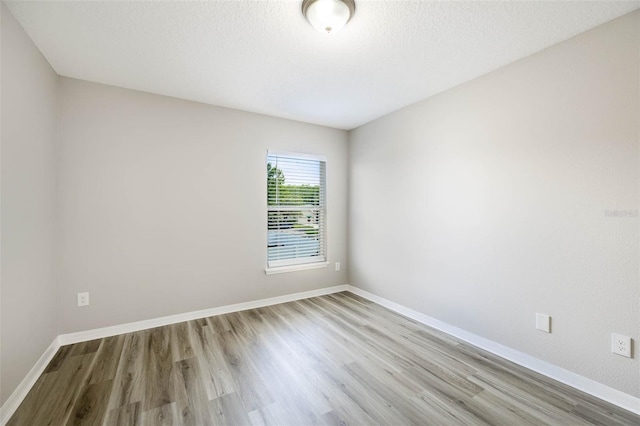 unfurnished room with light wood-type flooring and a textured ceiling