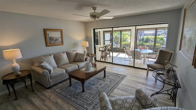 living room featuring a textured ceiling, wood-type flooring, and ceiling fan