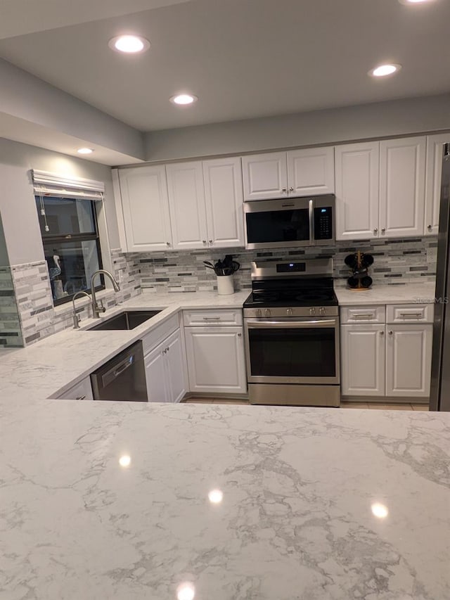 kitchen with appliances with stainless steel finishes, decorative backsplash, and white cabinets