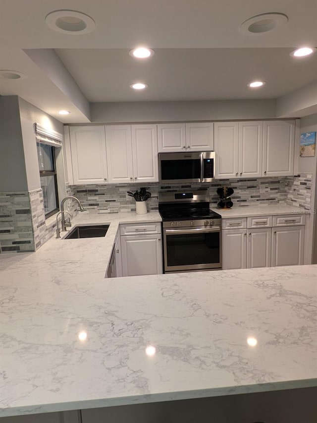 kitchen with stainless steel appliances, white cabinets, tasteful backsplash, and sink