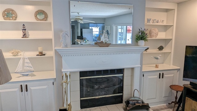 interior details with tile patterned flooring, ceiling fan, a fireplace, and a textured ceiling