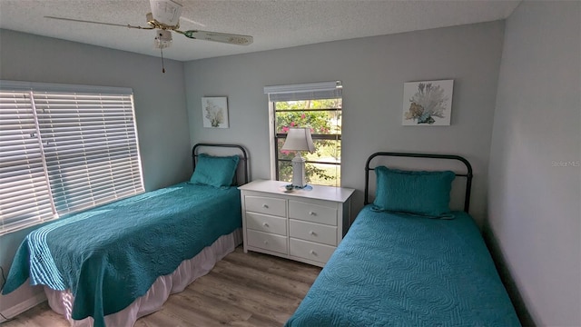 bedroom with light hardwood / wood-style floors, ceiling fan, and a textured ceiling