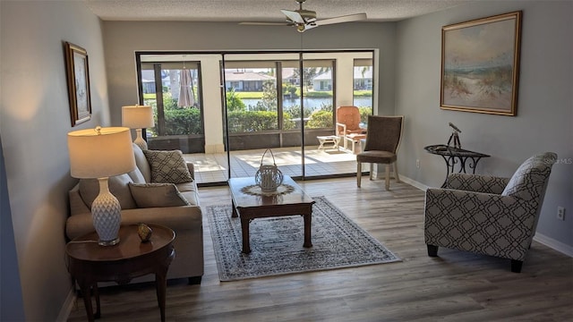 living room featuring wood-type flooring, ceiling fan, and a textured ceiling