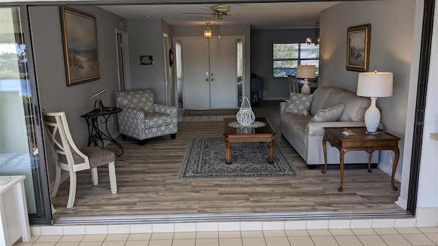 living room with ceiling fan with notable chandelier and light hardwood / wood-style flooring