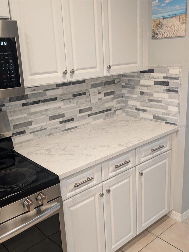 kitchen featuring light stone countertops, appliances with stainless steel finishes, backsplash, and white cabinetry