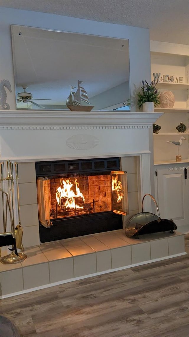 details with wood-type flooring, a tiled fireplace, and ceiling fan