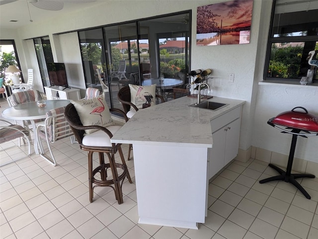 kitchen featuring light tile patterned flooring, white cabinets, kitchen peninsula, ceiling fan, and sink