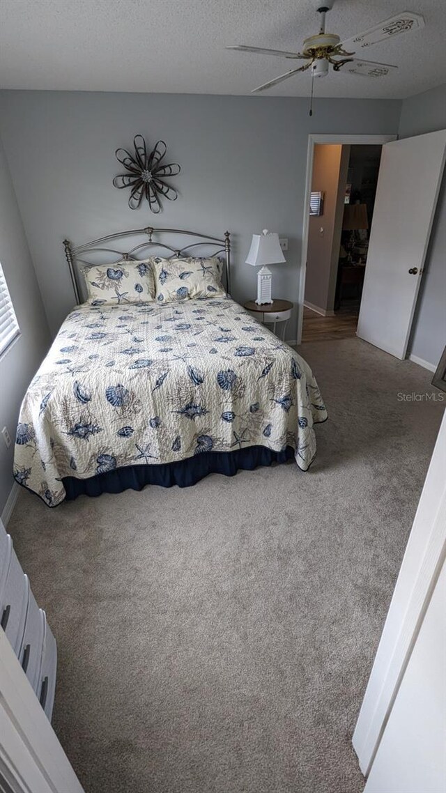 carpeted bedroom featuring ceiling fan and a textured ceiling