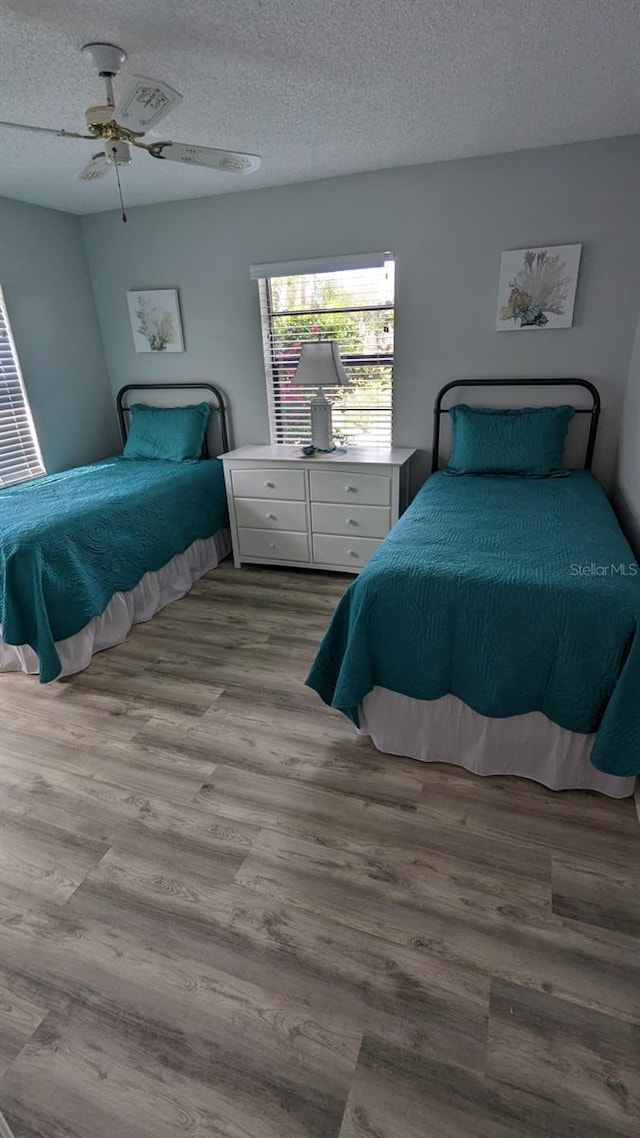 bedroom with a textured ceiling, ceiling fan, and light hardwood / wood-style flooring