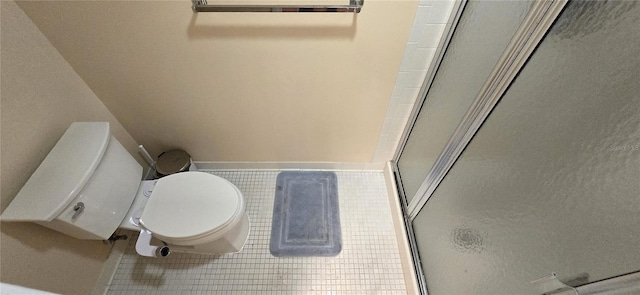 bathroom featuring a shower with door, tile flooring, and toilet