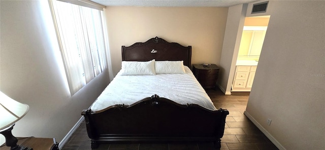 bedroom with dark hardwood / wood-style floors, multiple windows, and ensuite bath