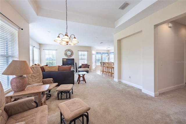 carpeted living room with a tray ceiling and a chandelier