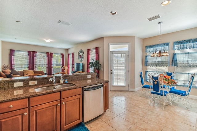 kitchen with dishwasher, hanging light fixtures, light tile floors, sink, and a textured ceiling