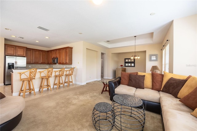 living room with a notable chandelier and a raised ceiling