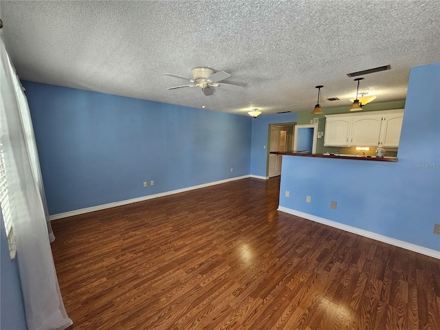 unfurnished living room with a textured ceiling, dark hardwood / wood-style floors, and ceiling fan