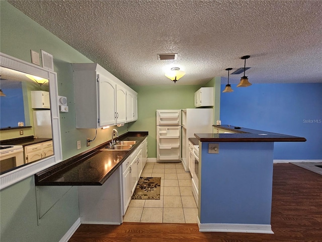 kitchen featuring sink, light tile floors, white cabinets, a textured ceiling, and pendant lighting