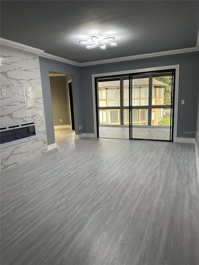 unfurnished living room featuring ornamental molding, hardwood / wood-style floors, a premium fireplace, and a textured ceiling