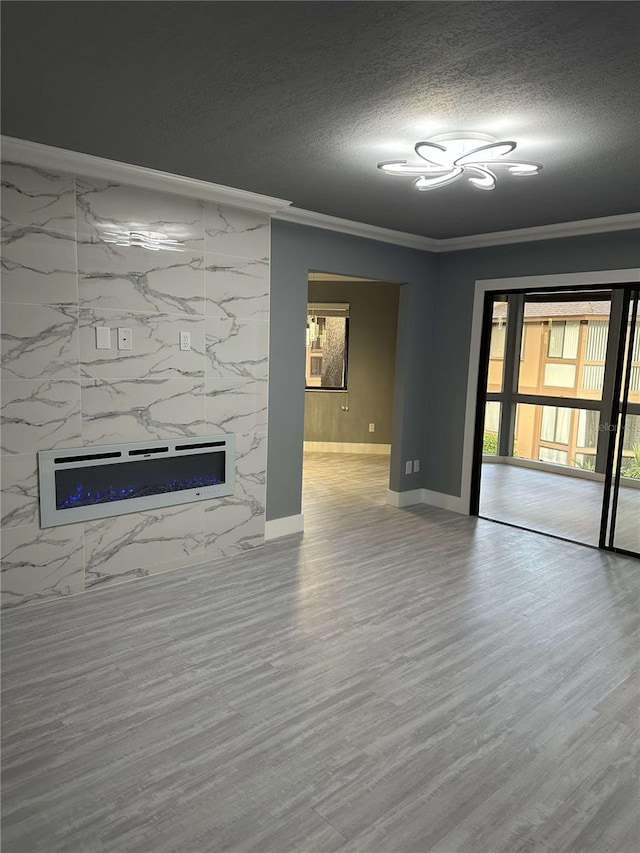 unfurnished living room with a premium fireplace, crown molding, a textured ceiling, and wood-type flooring