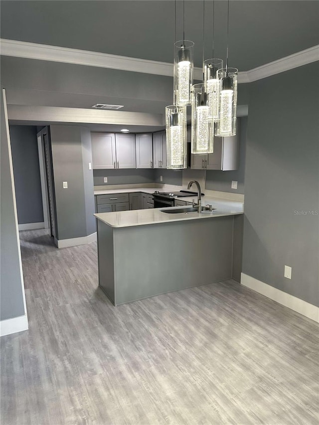 kitchen featuring gray cabinets, kitchen peninsula, hanging light fixtures, and light wood-type flooring