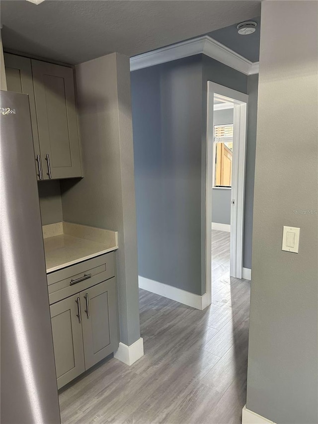 kitchen featuring gray cabinets, ornamental molding, and light wood-type flooring