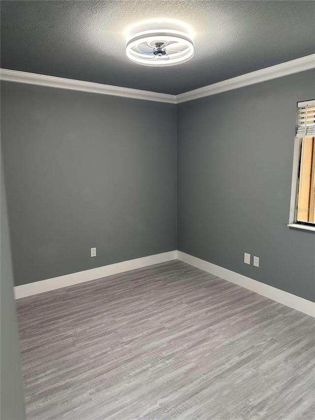 spare room featuring light hardwood / wood-style floors, a textured ceiling, and ornamental molding