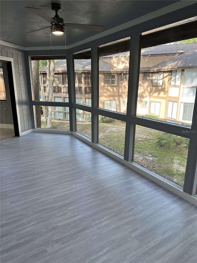 unfurnished sunroom with ceiling fan