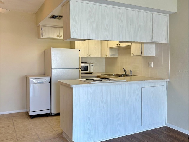 kitchen with backsplash, white appliances, kitchen peninsula, and sink